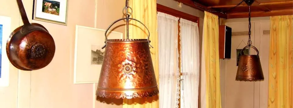 Zwei Leuchten aus getriebenem Kupfer und eine kupferne Pfanne an der Wand der Stube