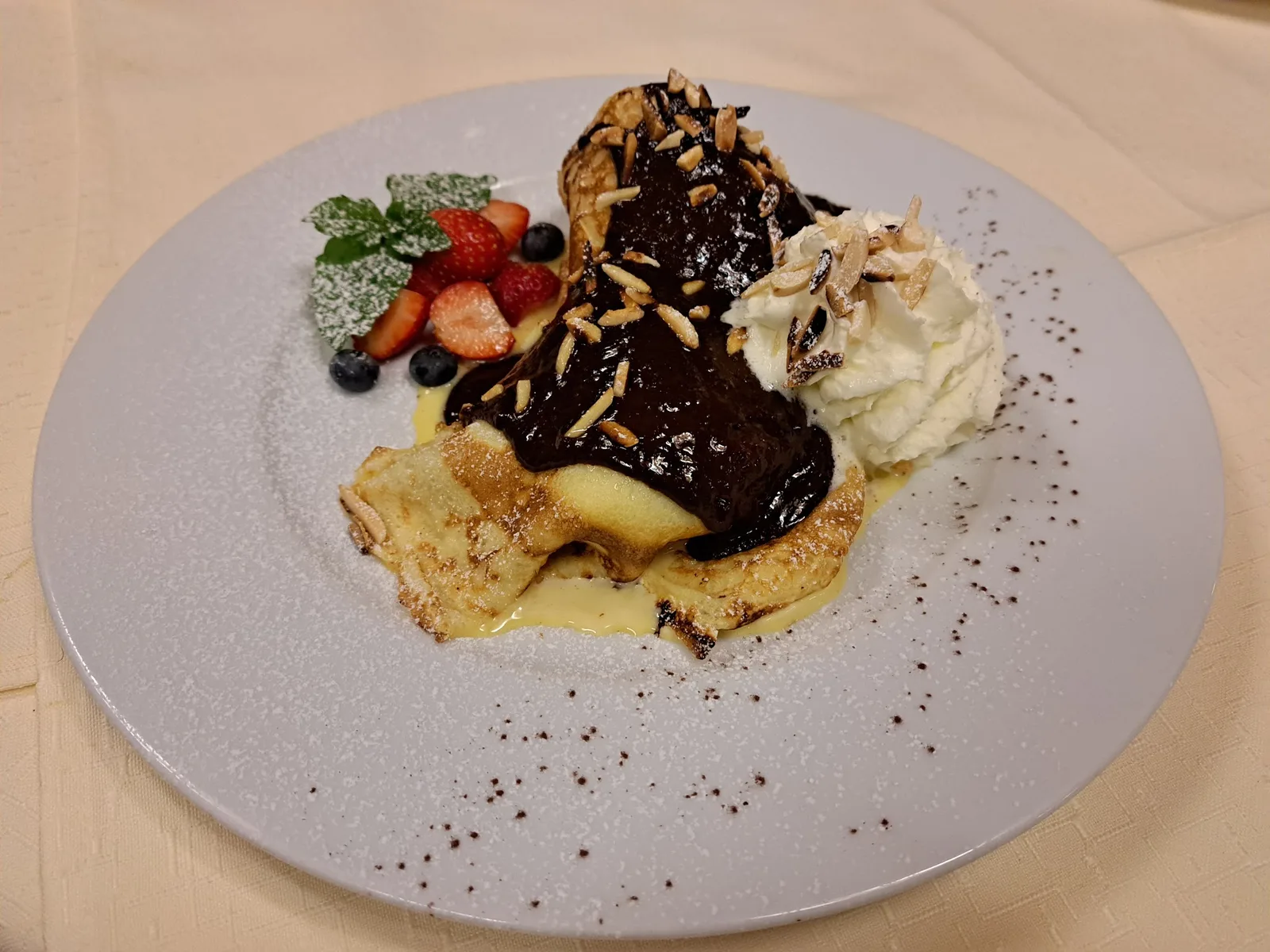 Palatschinke mit Schokosauce, gehobelten Mandeln, Beeren und Schlagobers