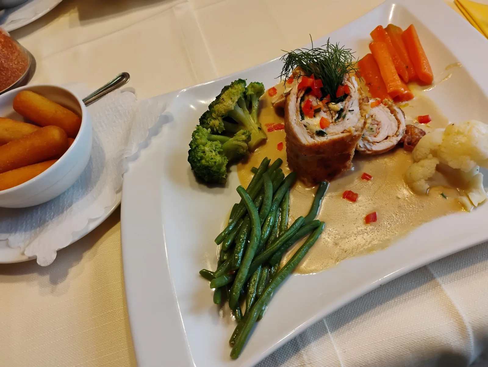 Putenfiletroulade mit Broccoli, Karotten, Fisolen und Kroketten