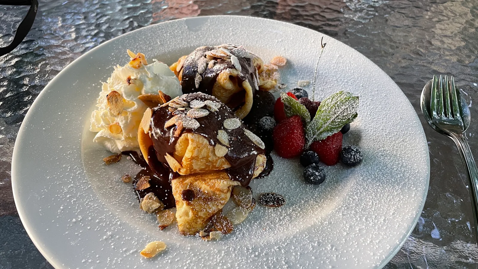 Zwei Palatschinken mit Schokosauce und frischen Beeren auf dem Terrassentisch